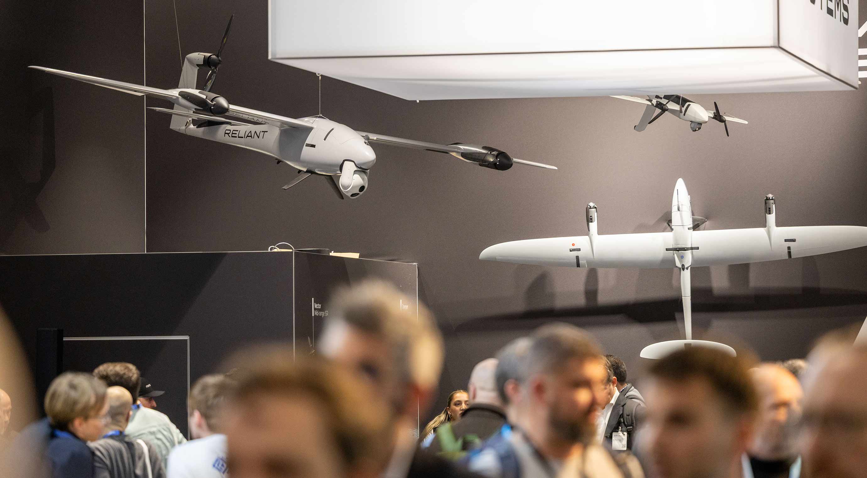 Drone models on display at the booth; visitors looking at unmanned aerial vehicles.