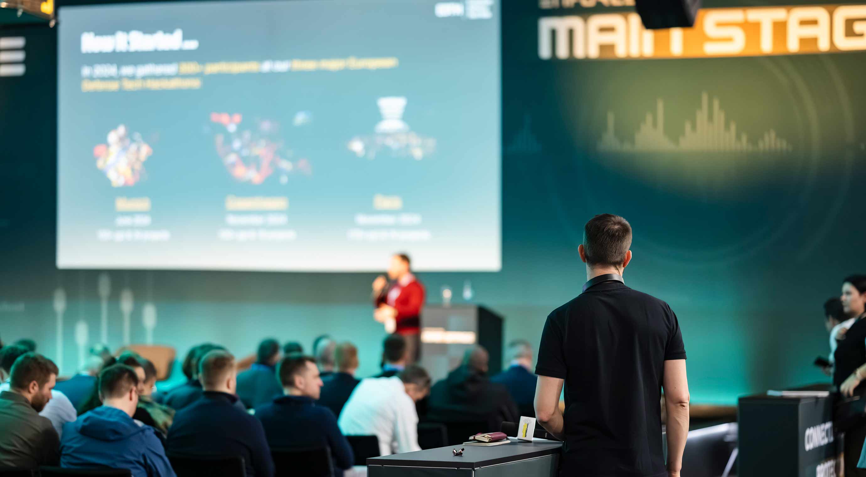 Audience at a specialized presentation at Enforce Tac, featuring a stage with a presentation and a large screen.