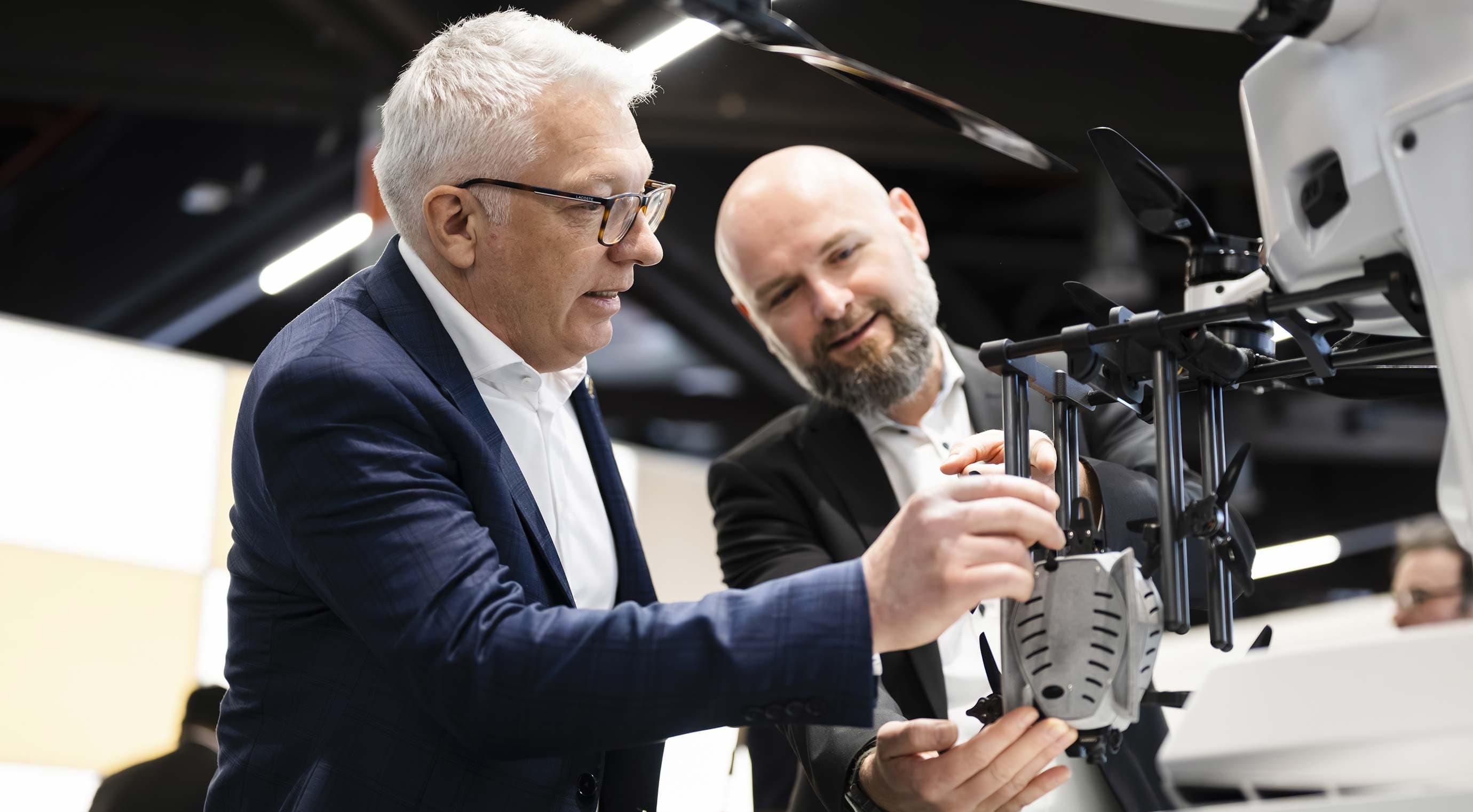 Two people are looking at a drone at the exhibition stand, explaining its components and functions in the exhibition hall.