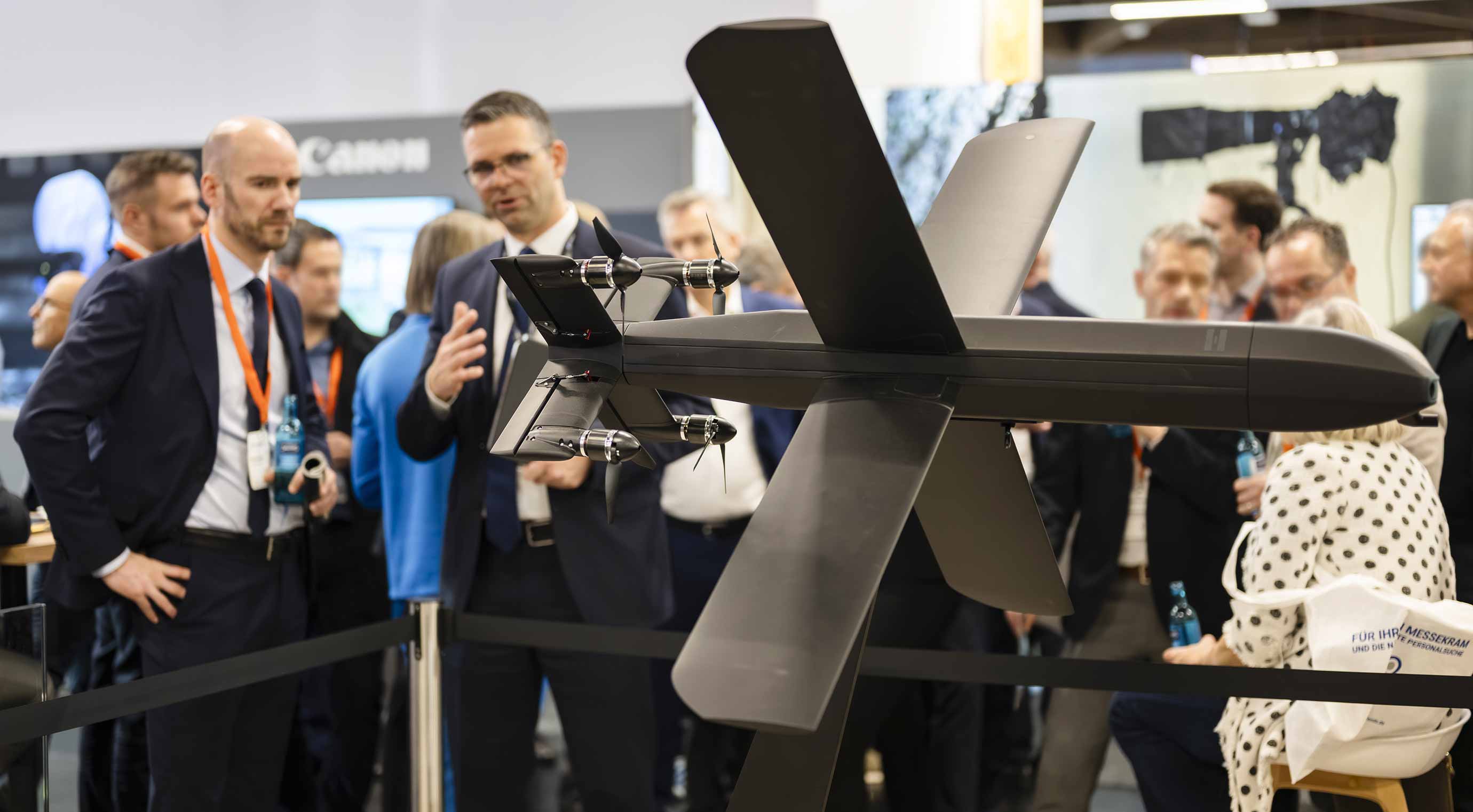 Presentation of a drone at the exhibition stand; trade visitors look at the unmanned vehicle.