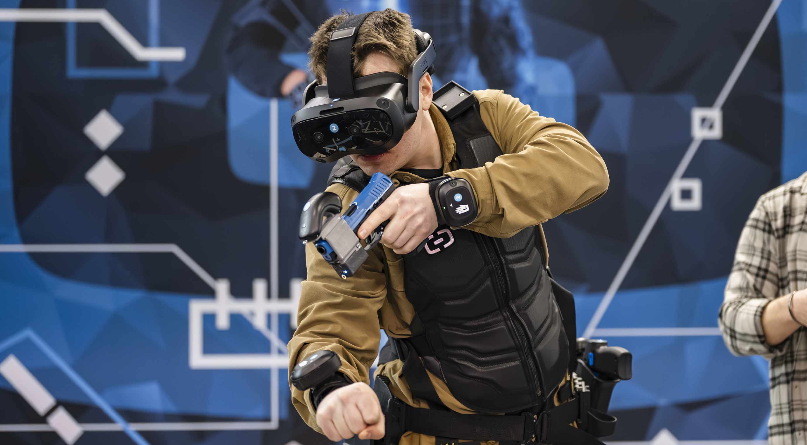 VR training at a trade fair: a visitor tries out a simulation using a headset and a training weapon at the stand.